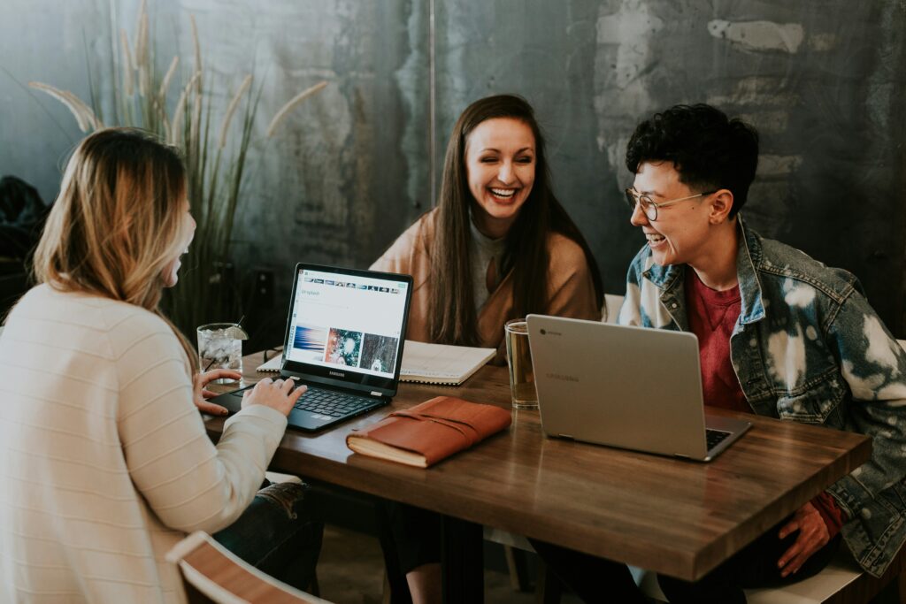 trois personnes travaillant sur leurs ordinateurs et rigolant ensemble